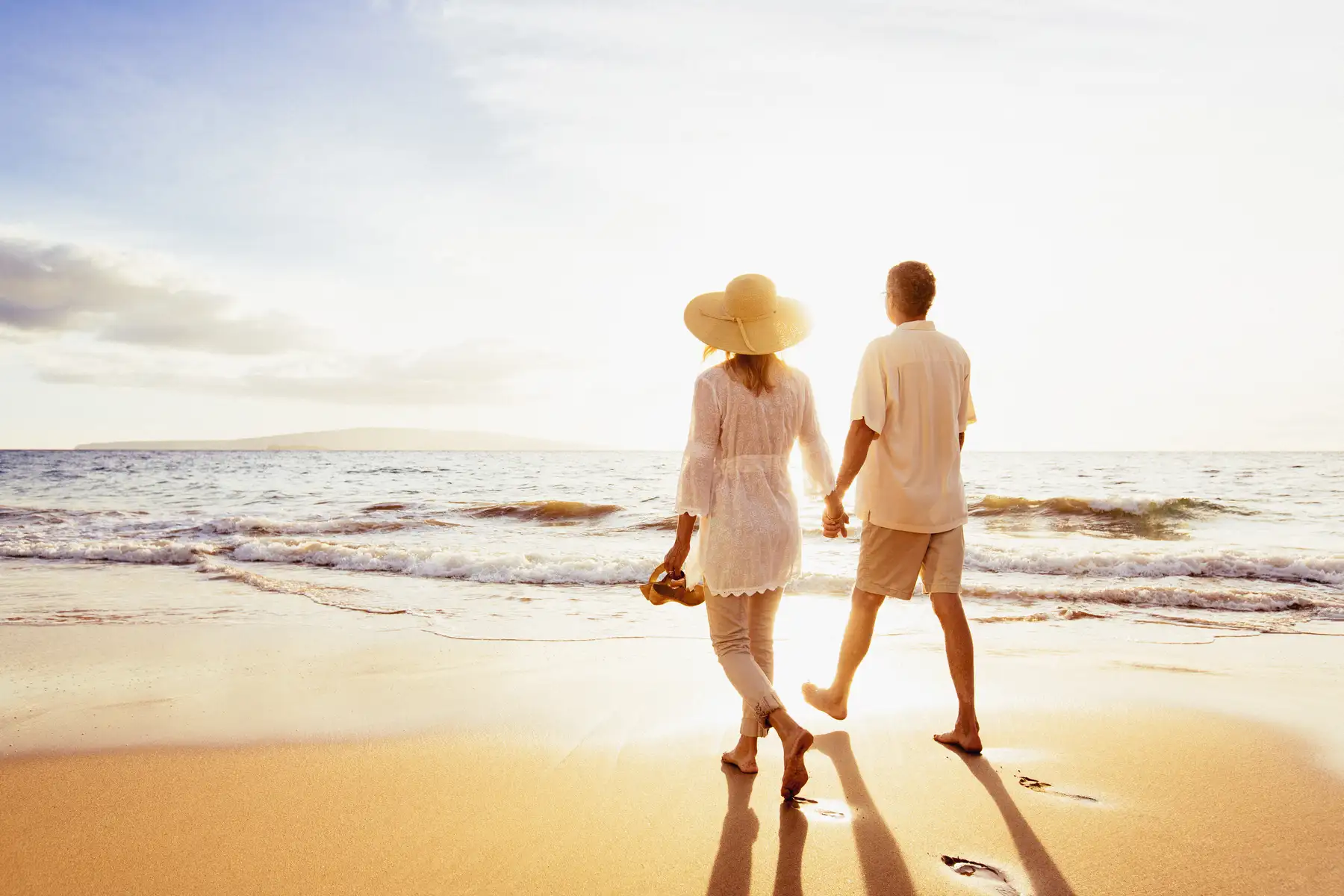 A couple of people walking along the beach near new luxury condos in Naples, FL during sunset